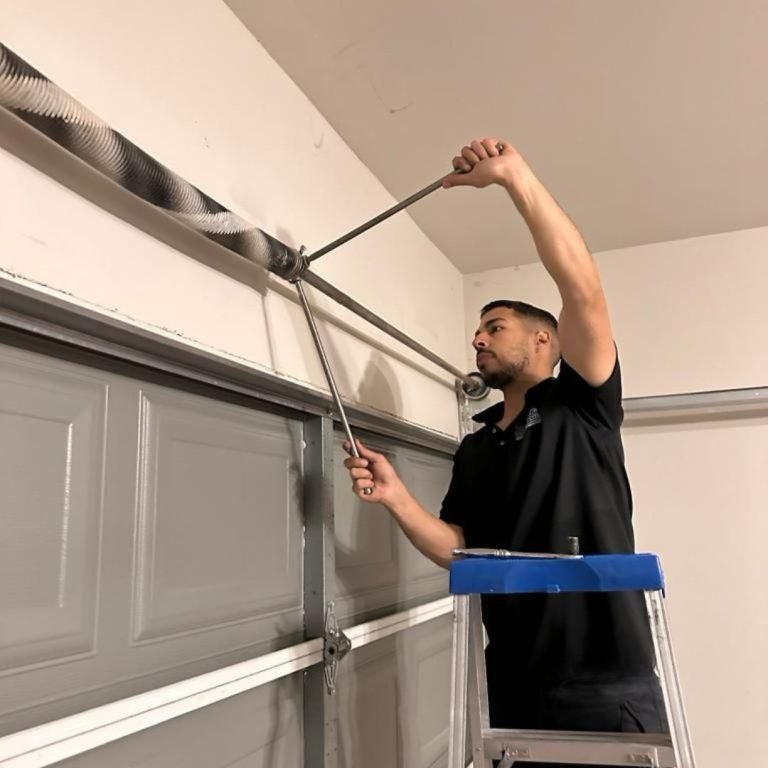 Garage Door Family technician setting the tension on a new torsion spring with winding bars