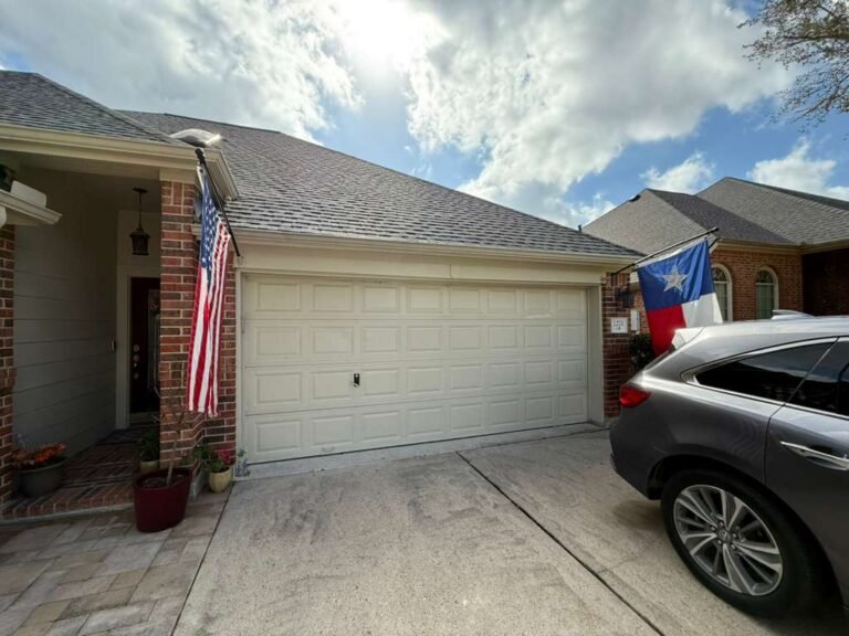 Double garage door on a brick home in the Katy area, with US and Texas flags flying by the entry