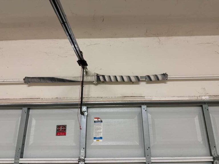 Snapped torsion spring above a garage door with a visible gap in the coil