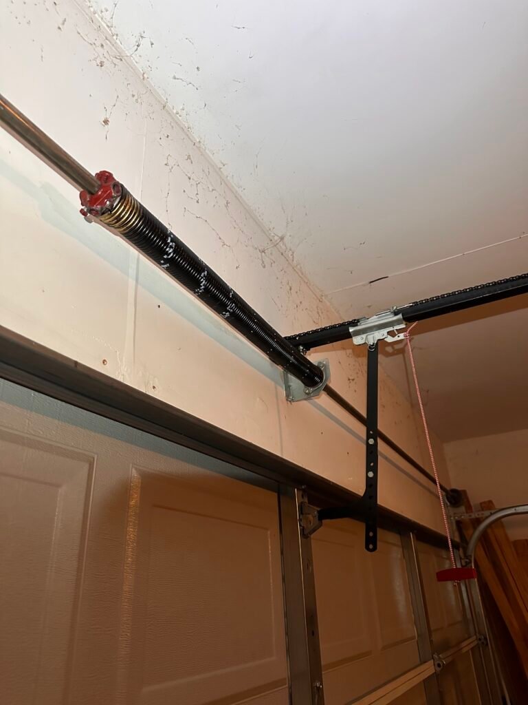 Torsion spring and shaft mounted above a garage door
